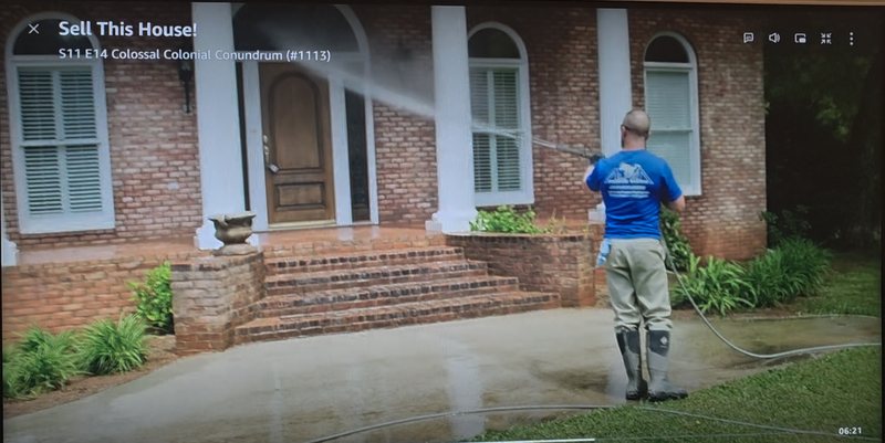 TV screen showing Sell This House S11 E14 Colossal Colonial Conundrum, with an Alpha Pressure Washing technician in a blue Alpha shirt pressure washing the brick front entry and walkway of a house