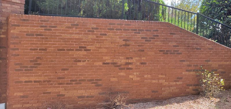 The same brick retaining wall after cleaning, with its red brick color restored