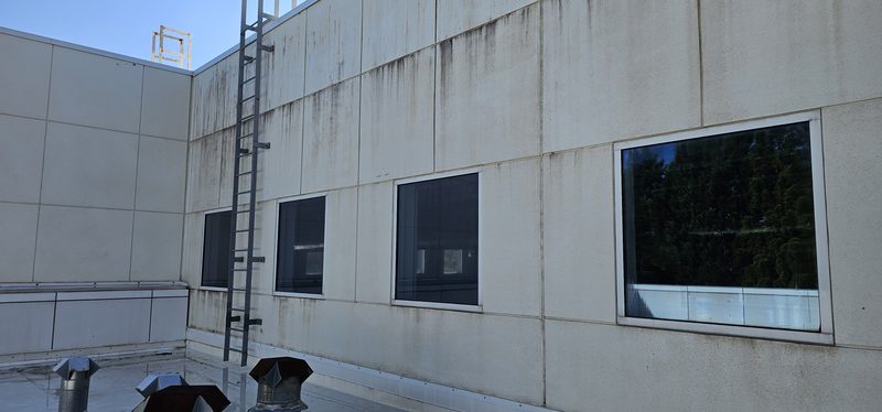 Streaked and stained panel wall on a commercial building rooftop before cleaning