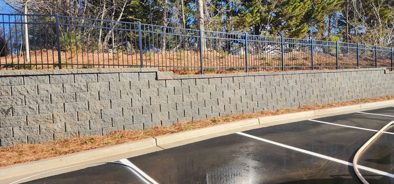 Long segmental block retaining wall beside a parking lot after washing