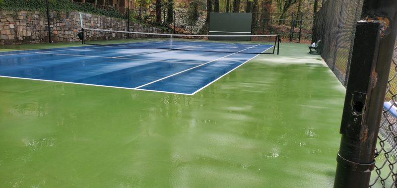 The same tennis court after cleaning, with bright blue and green court colors