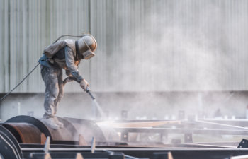 industial worker using sand blasting process