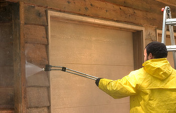 a man pressure washing a wood sided garage